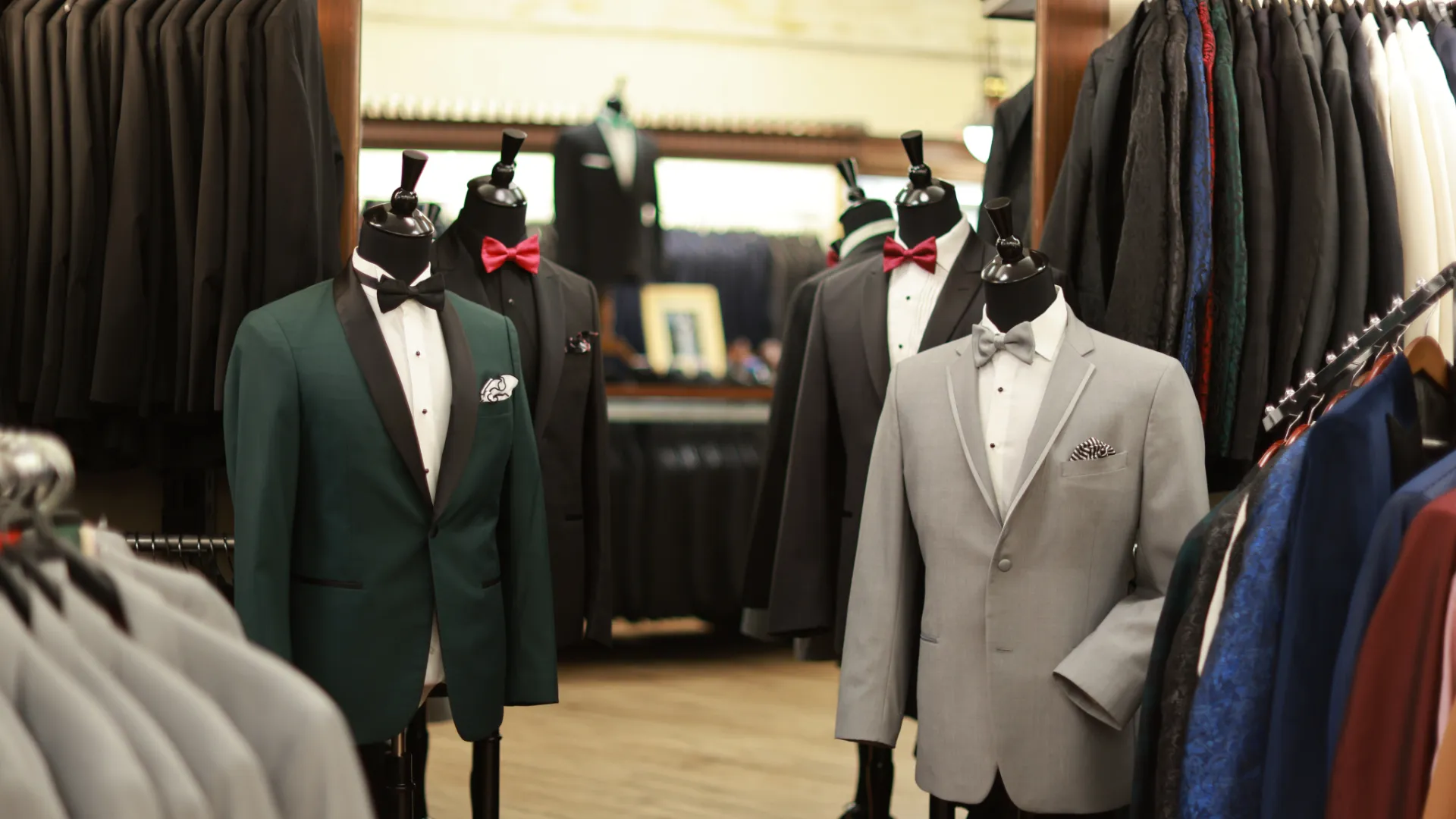 an assortment of suit jackets, pockets squares, and bow ties styled on mannequins