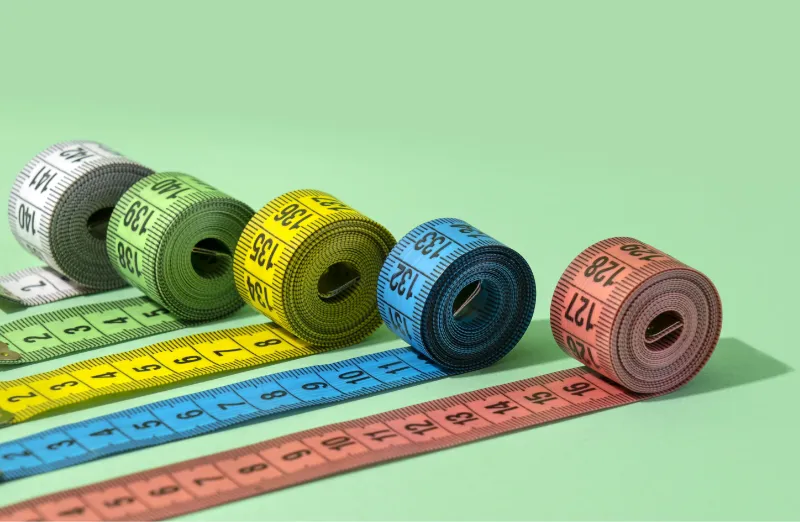 a variety of colors of measuring tape unrolling in a row