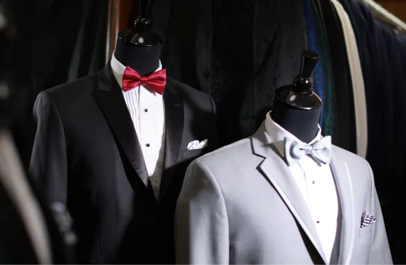 an assortment of suit jackets, pockets squares, and bow ties styled on mannequins